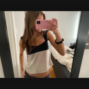 Svartvit linnetopp med breda axelband - Snygg linnetopp i svart och vitt med breda axelband och rak passform. 