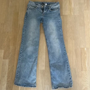Bootcut ljusblå jeans - Snygga bootcut jeans i ljusblå tvätt med klassisk femficksdesign och dragkedja. Jeansen har en rak passform över låren och blir vidare nedtill, vilket ger en cool retrovibe. Tillverkade i jeansmaterial med slitningar för en avslappnad look.