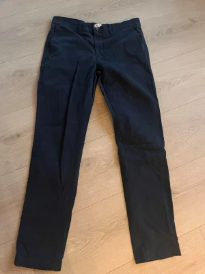 Mörkblå chinos från Boris Chiro, Dobber - Snygga mörkblå chinos från Boris Chiro, Dobber i slim fit-modell. Byxorna har klassisk design med knappgylf och bälteshällor. Perfekta för dig som gillar en smalare passform och stilren look.