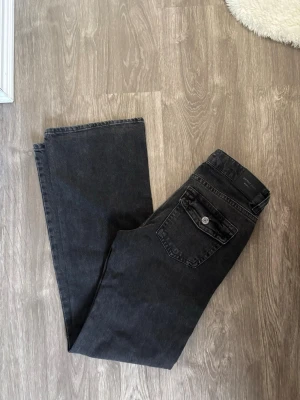 Jeans  - Grå, svarta jeans med knappar på fickorna, bootcut, har aldrig använt, felfria. Säljer de pga för små.