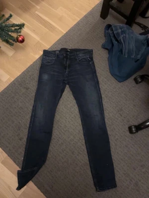 Mörkblå Replay jeans - Säljer ett par mörkblå skinny jeans med klassisk femficksdesign och smal passform. Jeansen har en lätt tvättad look och är tillverkade i stretchigt denimtyg för extra komfort. Perfekta för en trendig och avslappnad stil.