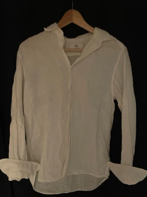 Vit linneskjorta - Klassisk vit skjorta i linne med lång ärm och avslappnad passform. Skjortan har en enkel krage och knappar framtill, perfekt för en clean och stilren look. Passar till sommarkvällar och bra nu på sommaren. Hör gärna av er om ni har några frågor eller funderingar! 