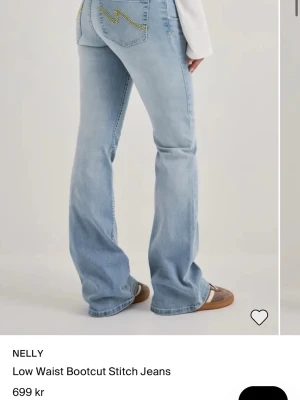 Bootcut ljusblå jeans med söm - Bootcut jeans i ljusblå denim från Nelly med låg midja och dekorativ gul söm på bakfickorna. Jeansen har en klassisk femficksmodell och är tillverkade i ett mjukt denimtyg som ger en avslappnad vibe.