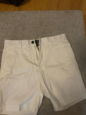 Vita shorts från H&M, regular fit - Snygga vita shorts från H&M i regular fit. De har klassisk design med knapp och dragkedja framtill samt hällor för bälte. Perfekta för varma dagar och enkla att matcha med olika toppar.