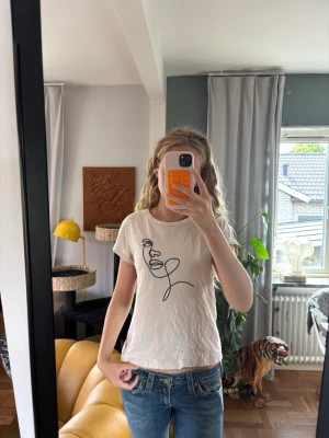 Vit t-shirt med broderat ansikte - Säljer en vit t-shirt från Lindex med ett svart broderat ansikte på framsidan. T-shirten har korta ärmar och är i mjuk bomull, perfekt till jeans eller kjol. Enkel men ändå unik design som sticker ut, tror den skulle ha jättestor potential om man bara syr om den lite!