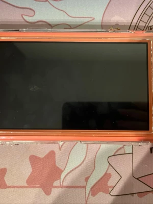 Nintendo Switch lite korallrosa konsol - Säljer en Nintendo Switch i snygg korallrosa färg med genomskinligt skyddsskal. Konsolen har en stor skärm och baksidan pryds av ett gulligt blomcharm. Perfekt för gaming hemma eller på språng! (Kommer ej med laddare) skriv om du har några frågor 😊
