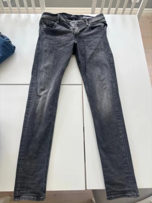 Grå slim fit jeans med slitningar - Ett par gör snygga grå slim fit replay jeans, med lite diskreta slitningar längst med knäna. Läng 32 i midjan är de 29! Hör av dig vid eventuella frågor..😀