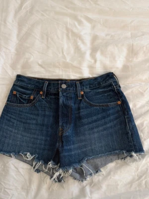 Levi's 501 mörkblåa jeansshorts  - Säljer mina Levi's 501 jeansshorts i mörkblå denim. Shortsen har hög midja, fem fickor röda Levi's-taggen på fickan. Perfekta till sommaren!