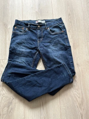 Mörkblå jeans från Levis - Mörkblå jeans från Levis 512 dem är lite trasiga på benet har de vart hål som sytts igen och lappen där bak låssna lite. Hör av vid funderingar