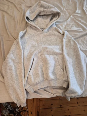 Ljusgrå hoodie från 157 - Ljusgrå hoodie från 157 i storlek XS. Klassisk modell med stor huva och magficka. Tillverkad i mjukt och skönt material med ribbade muddar vid ärmar och nederkant. Perfekt för en avslappnad och chill stil.
