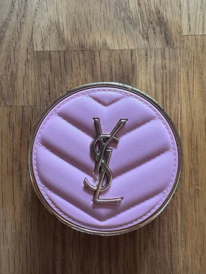 YSL  rosa rouge - färg 42 - bra för dig som har ljus hy. ett exklusivt rosa rouge från Yves Saint Laurent i en rund dosa med quiltad, ljusrosa ovansida och guldfärgade detaljer. Dosan har YSL-loggan i metall och rouget har en mjuk, matt finish som ger en fräsch look.