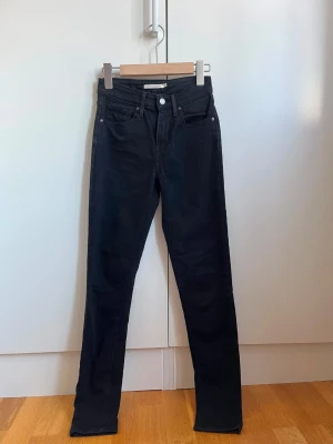 LEVI'S - high rise skinny jeans - Säljer ett par svarta high rise skinny jeans i modellen 721. Jeansen har fem fickor, bälteshällor och knappgylf. Snygg, tight passform med hög midja som framhäver siluetten. Perfekta till en trendig och clean look.