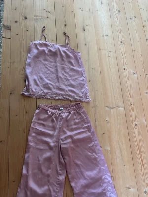 Ljuslila satinpyjamas med spets - Säljer ett set med ljuslila pyjamas i satin. Linnet har tunna axelband och spetsdetaljer längst ner. Byxorna är vida med resår i midjan för extra komfort. Dock en liten fläck på ena byxbenet, men jag ska försköka få bort den i tvätten! Väldigt skön! ( priset går att diskutera)💗