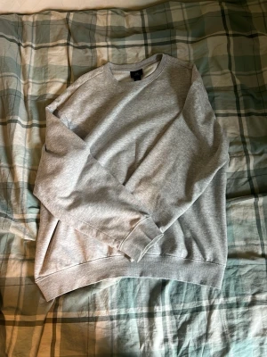 Grå basic sweatshirt - En stilren grå sweatshirt i klassisk modell med rund hals och långa ärmar. Tröjan har ribbade muddar vid ärmslut och nederkant. Perfekt för en avslappnad och enkel look.