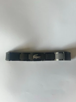 Lacoste armband svart - Säljer mitt Lacoste armband i rostfritt stål. Det är bara använt ett fåtal gånger därav det mycket bra skicket. Det är 20 cm långt men det går att förkorta till 18 med länkarna som syns på bilderna. Hör av er om ni har mer frågor! Mvh Loke