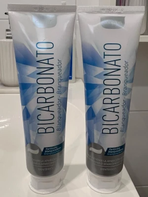 1 BICARBONATO tandkräm whitening. - Tandkräm med bikarbonat och whitening-effekt. Tuben är vit med blått och silvermönster. Innehåller bland annat glycerin, natriumbikarbonat och mentol för fräsch andedräkt och vitare tänder. Volym: 100 ml. Märkt med Mercadona.