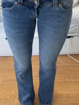 Blå lågmidjade jeans från Abrand Jeans - Säljer ett par blå bootcut superlågmidjade jeans från Abrand. Storlek 24 tall. Personen på bilden är 174. Köpta för 999kr.