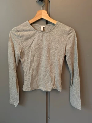 Ljusgrå långärmad topp från Nelly - En enkel och stilren ljusgrå långärmad topp med rund halsringning. Toppen är i ett mjukt och stretchigt material som sitter bekvämt på kroppen. Perfekt att matcha med jeans eller kjol för en clean look.