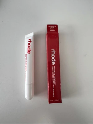 Rhode Peptide Lip Treatment Strawberry - Rhode Peptide Lip Treatment i smaken Strawberry Glaze. Kommer i en vit tub med röd text och matchande röd förpackning. Tuben rymmer 10 ml och har en smidig applikator. Perfekt för att återfukta och ge glans till läpparna.