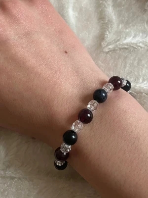 Armband med svarta och vinröda pärlor - Armband med växelvis svarta och vinröda pärlor samt transparenta facetterade pärlor. Elastiskt band gör det enkelt att ta på och av. 😊