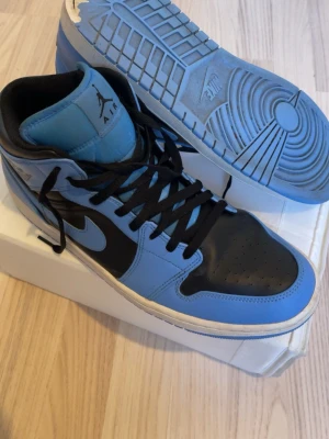 Air jordan 1 Mid Unviversity Blue/black - Säljer ett par riktigt snygga Air Jordan 1 Mid i färgkombinationen University Blue/Black. Skorna är inköpta på Foot Locker för 1600 kr och är i mycket bra skick då de har tagits väl hand om. Kan hämtas eller mötas upp.      Övrigt: Säljs utan originalkartong (säljs självklart packat på annat tryggt sätt)