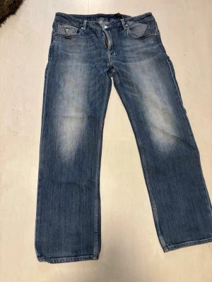 Jeans - Säljer ett par klassiska blå jeans med raka ben och snygga slitningar på framsidan. Jeansen har fem fickor och normal midja. Perfekta till vardagslooken och passar till det mesta. Materialet är denim i bomull.