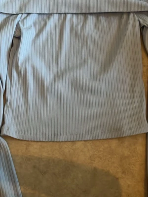 Ljusblå offshoulder ribbad topp - Trendig ljusblå och vit  offshoulder topp med ribbad struktur och långa ärmar. Används ej längre de en som är vit och en som är ljusblå