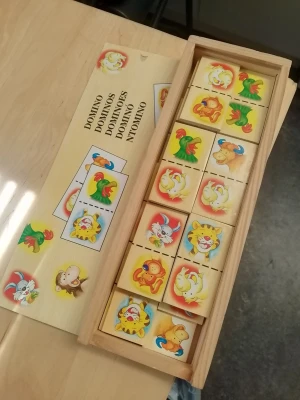 Trädomino med djurmotiv - Säljer ett trädomino med färgglada djurmotiv som lejon, apa, papegoja och elefant. Brickorna är gjorda av trä och kommer i en praktisk trälåda med skjutlock. Perfekt för spelkvällar eller som pedagogiskt spel för yngre barn.