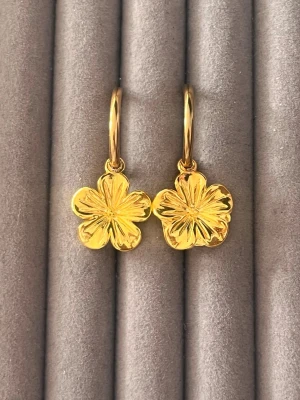 Guldpläterade blomörhängen - Säljer ett par snygga örhängen i guldpläterad metall med blommotiv. Hängena har en detaljrik, glansig yta och är formade som fembladiga blommor. Perfekta för dig som gillar unika accessoarer med naturinspirerad design.