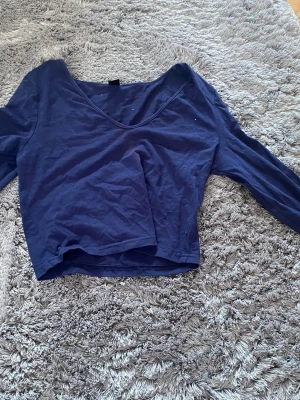 Mörkblå croppad långärmad topp - Snygg mörkblå croppad topp med lång ärm och v-ringning. Perfekt till jeans eller kjol för en trendig look. Tillverkad i mjukt bomullsmaterial som känns skönt mot huden.