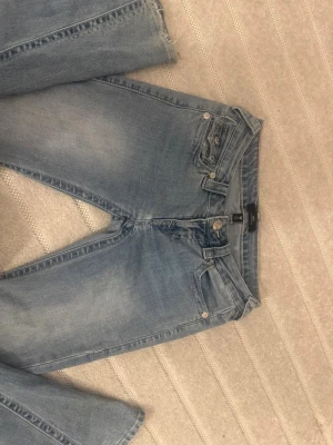 Ljusblå bootcut jeans True Religion - Säljer ett par ljusblå bootcut jeans från True Religion med klassiska kontrastsömmar och fickdetaljer bak. Jeansen har normal midja och fem fickor. Perfekta för en avslappnad och trendig look. Storlek 25, modell joey. Så lågmidjade. 