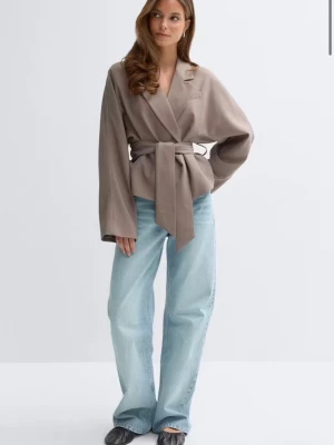 Beige kavaj med knytskärp - Stilren beige kavaj med breda slag och knytskärp i midjan. Kavajen har en avslappnad passform, långa ärmar och är tillverkad i ett mjukt tyg som ger en lyxig känsla. Perfekt för dig som vill ha en modern och trendig look.