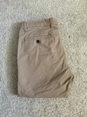 Dressmann Chinos - 31/34 - Beige chinos från Dressmann i Slim Fit, storlek 31/34. Väldigt sparsamt använda och i mycket bra skick!   📦 Snabb leverans! 💬 Hör gärna av dig vid frågor eller om du vill ha fler bilder/mått!