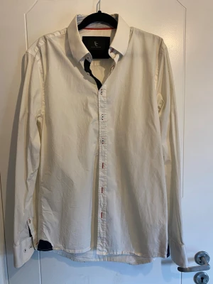 Vit skjorta från Savvy Citizen - Klassisk vit skjorta från Savvy Citizen i storlek medium. Skjortan har långa ärmar, knappar framtill och kontrastdetaljer i krage och manschetter. Perfekt för en clean och stilren look.