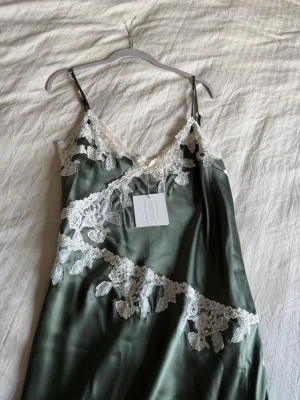 By Malene Birger VERA satinklänning  - Helt oanvänd By Malene Birger VERA satinklänning i en fantastisk fin grön färg med vita broderier. Ordinarie pris 4495kr. Storlek 44