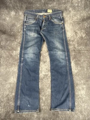 Blå Wrangler Ace-jeans för herrar i storlek W32 L34 - Snyggt slitage på låren och vid fickorna. Bekväm och klassisk Wrangler-modell.  Skick: 9,5/10  Midja: 43 cm Benslut: 22 cm Lår: 30 cm Totallängd: 107 cm Måtten finns även på bilderna  Skickas inom ett dygn På min profil finns fler jeans.     D89