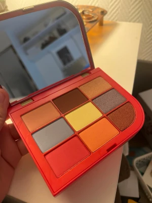 BeautyAct Vibrant To Go Ögonskuggspalett - Färgstark ögonskuggspalett med nio nyanser i matta och skimrande toner. Innehåller gult, orange, rött, brunt, koppar, silver och persika. Kommer i en röd kompakt dosa med spegel, perfekt för att skapa kreativa och intensiva ögonlooks.