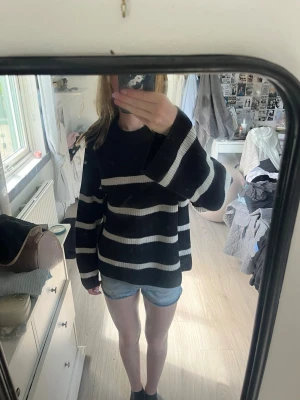 Svartvit randig stickad tröja - Säljer en oversized stickad tröja med breda svarta och vita horisontella ränder. Tröjan har långa ärmar och en avslappnad passform, perfekt för en chill och trendig look. Materialet ser mjukt och bekvämt ut, perfekt för lager på lager.