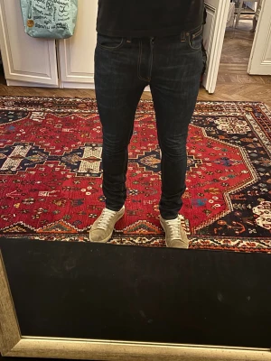 Nudie jeans Grim Tim - NUDIE JEANS GRIM TIM  Storlek: W31/L32  Passform: Slim fit  Använding: Jeansen är i väldigt fint skick utan defekter  Modellen på bilden: 185CM och väger 80KG