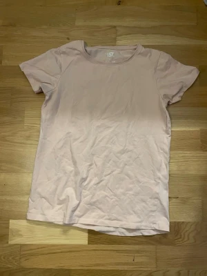 Ljusrosa t-shirt från 157 - En enkel och stilren ljusrosa t-shirt från 157. T-shirten har rund halsringning och korta ärmar. Tillverkad i mjuk bomull som känns skön mot huden. Perfekt till jeans eller shorts för en avslappnad look.