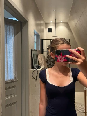 Mörkblå croppad topp med spets - Säljer en mörkblå croppad topp med korta ärmar .Toppen har en slim passform och är perfekt för dig som gillar en enkel men ändå söt stil. Passar till jeans eller kjol för en chill look.