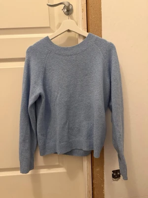 Ljusblå stickad tröja Vero Moda - Mysig ljusblå stickad tröja från Vero Moda med rund halsringning och ribbade muddar vid ärmslut och nederkant. Perfekt för lager på lager och enkel att matcha till jeans eller kjol.