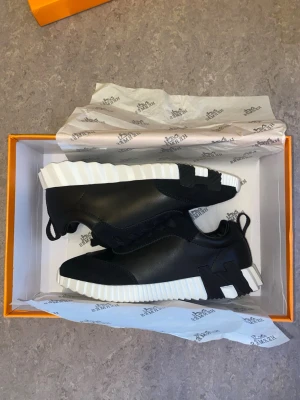 H H skor  - Snygga svarta sneakers med chunky, räfflad vit sula och svarta detaljer. Skorna har en modern design med släta partier i läderimitation och textil, samt dragflik bak för enkel påtagning. Perfekta för dig som gillar streetwear och vill sticka ut.