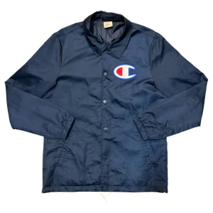 Champion Navy Coach Jacket - Den här varan kommer auktioneras ut på Sneakershyllan x Plick Live Torsdagen 10 september kl 19 med ett startpris på endast 10 kr❗️Marinblå coachjacka från Champion i mycket gott skick. Storlek small