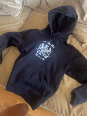 Svart hoodie från BVALDI med tryck - Svart hoodie från BVALDI med stort vitt tryck på framsidan är väldigt skön varm och snygg tröja med storlek S