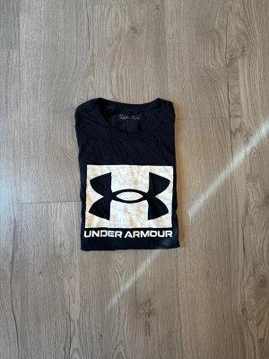 Svart Under Armour t-shirt - Snygg svart t-shirt från Under Armour med stort logotryck i vitt och beige på bröstet. Tröjan är i storlek XL📐! Tröjan är använd, men är fortfarande i ett riktigt bra skick och har inga defekter! Denna tröja ligger ungefär för 449 nypris! Skriv vid funderingar!✅ Postar inom 24h🚚📦!