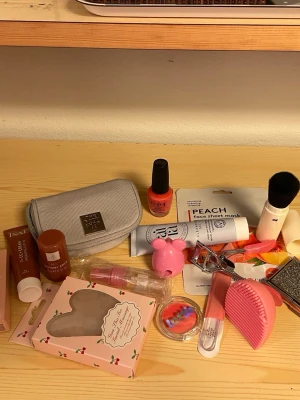 Stort skönhetspaket med smink och tillbehör - Ett blandat paket med skönhetsprodukter som inkluderar sminkväska i ljusgrått tyg från The Body Shop med spegel i, persikofärgat nagellack, ansiktsmask, highlighter, CC-kräm, bronzer stick (obs, provat på handen), sminkborste med lock, ögonfransböjare, ansiktsmassagegrej, ansiktsrengöring, sminkborsterengörare, ögonskugga från Lottie, kreditkortshållare, nagelfil i glasoch tom flaska. Perfekt för dig som gillar att testa olika produkter!
