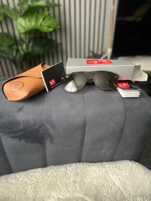 Ray-Ban bruna solglasögon - Säljer ett par Ray-Ban solglasögon med brunmelerad båge och mörka glas. Klassisk rektangulär form och Ray-Ban-logga på linsen. Kommer med originalfodral och box. Perfekta för soliga dagar och ger en tidlös look.