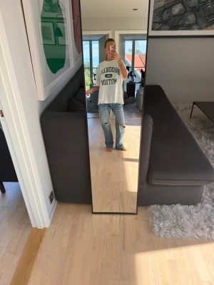Baggy ljusblå jeans med slitningar - Säljer ett par baggy ljusblå jeans med raka ben och slitningar på knäna. Jeansen har klassisk femficksdesign och är tillverkade i denim. Perfekta för en avslappnad och trendig look.