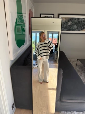 Vit oversized tröja med marinblå ränder - Säljer en oversized vit tröja med breda marinblå horisontella ränder. Tröjan har rund halsringning och långa ärmar med avslappnad passform. Perfekt för en chill och trendig look.